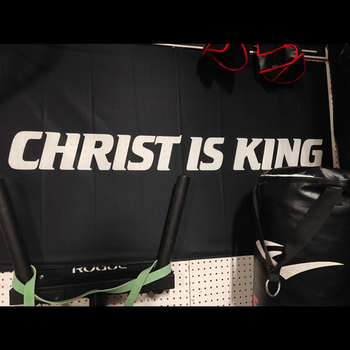 Black bag with 'Christ is King' flag, boxing gloves, and gym equipment on a black background.