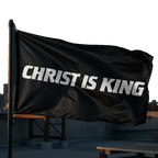 Black flag with 'CHRIST IS KING' text on a rooftop with city skyline in the background