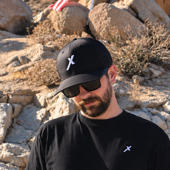 Man wearing black SIGNUMX Cross Hat with embroidered white X, outdoor lifestyle